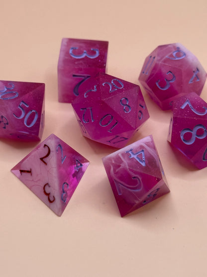Set of pink and white polyhedral dice on a beige background