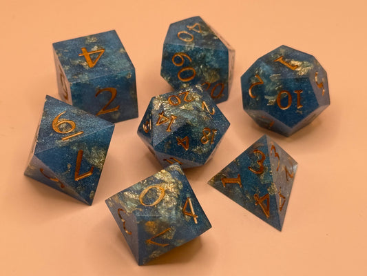 Set of blue polyhedral dice with gold numbers on a peach background
