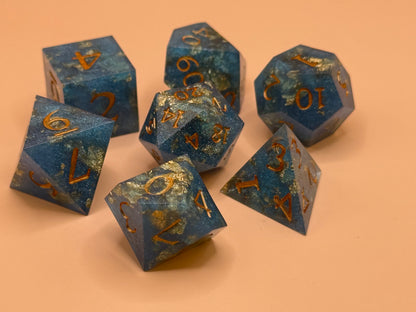 Set of blue polyhedral dice with gold numbers on a peach background