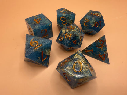 Set of blue polyhedral dice with gold numbers on a beige background