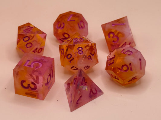 A purple and orange set of seven polyhedral resin dice on a white surface.