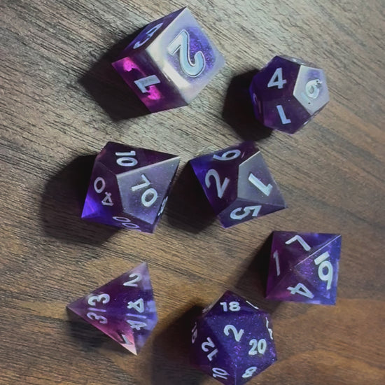 A video of polydactyl sharp-edge, a set of seven in blue and purple on a wood able. Numbers are inked in white.